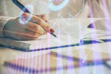 Double exposure of woman's hands making notes with forex graph hologram. Concept stock market analysis.