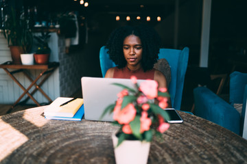 Dark skinned female author of romance working on new chapter for best seller sitting at table in...