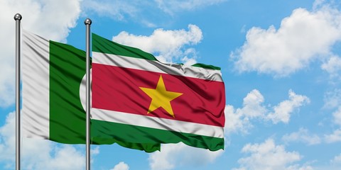 Pakistan and Suriname flag waving in the wind against white cloudy blue sky together. Diplomacy...