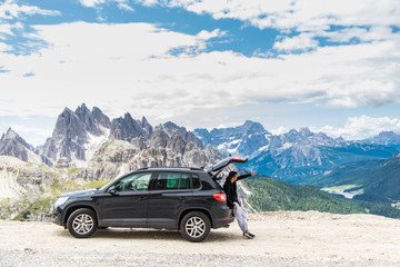 Young handsome man sitting in car trunk on the top of mountains road and pointed with hands on beauty landscape © F8  \ Suport Ukraine