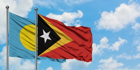 Palau and East Timor flag waving in the wind against white cloudy blue sky together. Diplomacy concept, international relations.