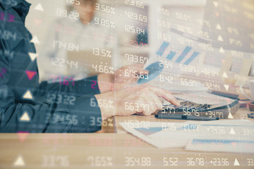 Double exposure of graph with man typing on computer in office on background. Concept of hard work. Closeup.