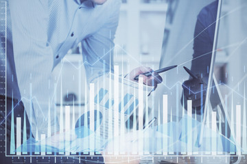 Double exposure of chart with businessman typing on computer in office on background. Concept of...