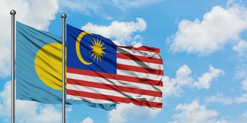 Palau and Malaysia flag waving in the wind against white cloudy blue sky together. Diplomacy concept, international relations.