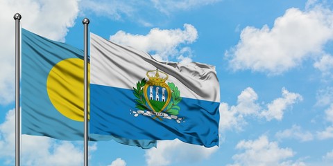 Palau and San Marino flag waving in the wind against white cloudy blue sky together. Diplomacy...