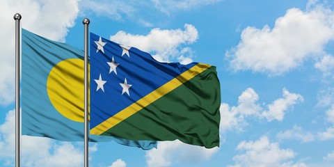 Palau and Solomon Islands flag waving in the wind against white cloudy blue sky together. Diplomacy concept, international relations.