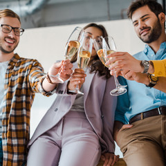 selective focus of cheerful businessmen and businesswomen toasting champagne glasses in office