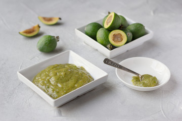 Mashed raw feijoa jam in white rectangle plate and feijoa fruits, healthy subtropical plant full of vitamin C, grown mostly  in Latin America