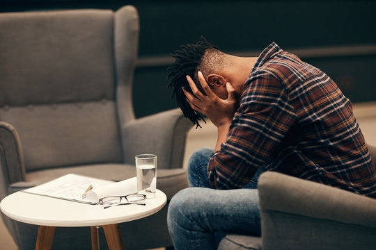 African Young Man Sitting On Sofa And Holding His Head He Is Very Dissapointed With Situation