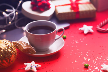 Preparing for Christmas: laptop, daily planner, cup of coffee, gifts, and decorations on the red background. Top view. Space for a text.