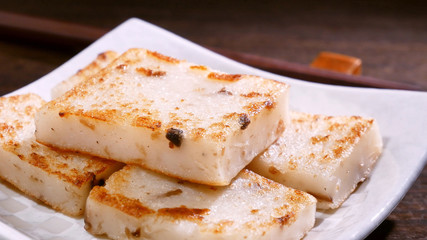 Pouring black soy sauce on ready-to-eat delicious turnip cake, Chinese traditional local dish...
