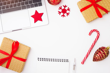 Fototapeta premium Preparing for Christmas: laptop, daily planner, cup of coffee, gifts, and decorations on the white background. Top view. Space for a text.