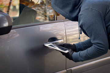 Hooded thief tries to break the car's security systems with tablet