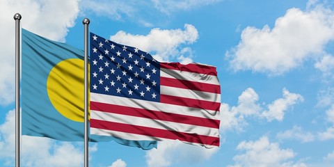 Palau and United States flag waving in the wind against white cloudy blue sky together. Diplomacy concept, international relations.
