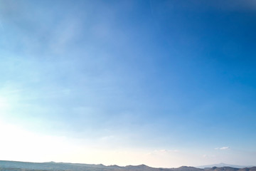 Bright autumn blue sky with white clouds and mountains at the horizon. Background or texture image with copyspace