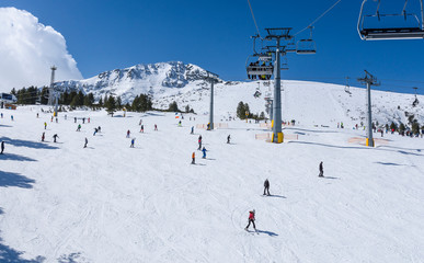 Fototapeta na wymiar Chair lift to the Todorka peak and skiers on the slope