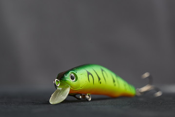 Fishing lure green used Wobbler closeup on gray background. Hooks and background in blur.