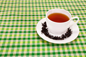 Black tea in a white cup on textile background. Copy space.