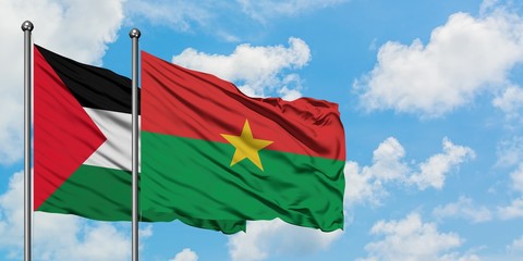 Palestine and Burkina Faso flag waving in the wind against white cloudy blue sky together....