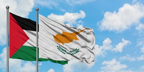 Palestine and Cyprus flag waving in the wind against white cloudy blue sky together. Diplomacy...
