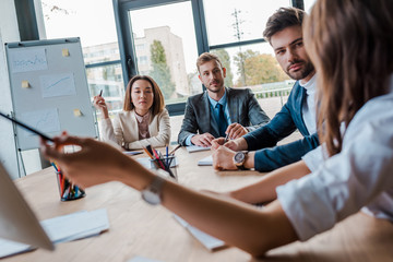 selective focus of multicultural businesspeople looking at coworker in office