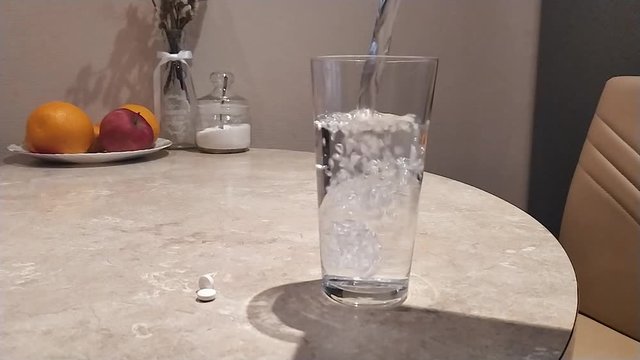 Clean water pouring into transparent glass on the table, coffee kitchen background