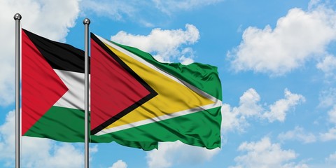 Palestine and Guyana flag waving in the wind against white cloudy blue sky together. Diplomacy...