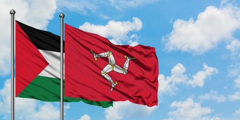 Palestine and Isle Of Man flag waving in the wind against white cloudy blue sky together. Diplomacy...