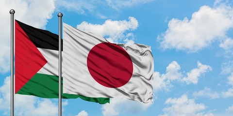 Palestine and Japan flag waving in the wind against white cloudy blue sky together. Diplomacy...