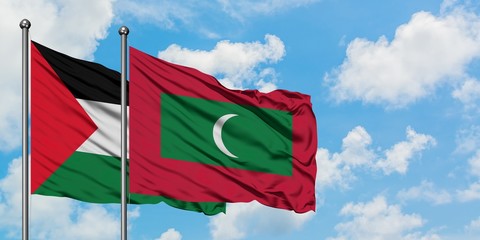 Palestine and Maldives flag waving in the wind against white cloudy blue sky together. Diplomacy...