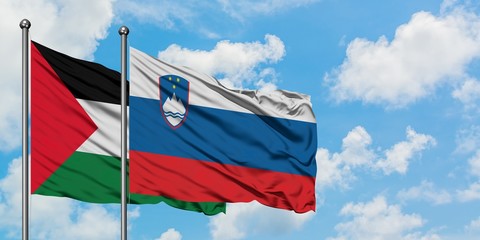 Palestine and Slovenia flag waving in the wind against white cloudy blue sky together. Diplomacy...