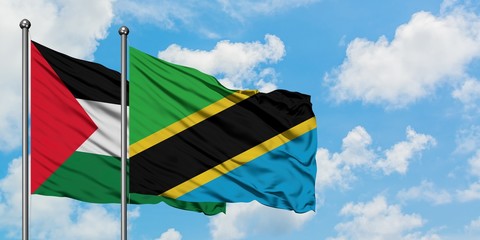 Palestine and Tanzania flag waving in the wind against white cloudy blue sky together. Diplomacy...