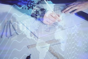 Double exposure of man's hands writing notes of stock market with forex chart.