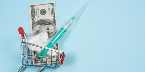 Full shopping cart with pills and money on blue background. Pharmacy concept.