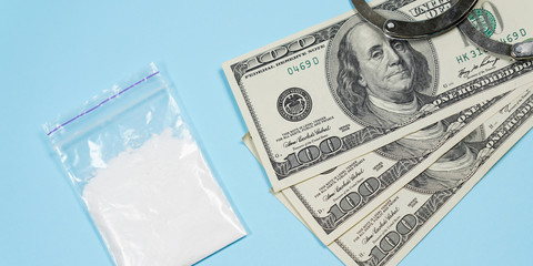 A bag of drugs, US dollars and handcuffs on the table.