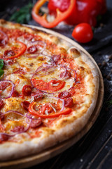Pizza with sausages, ham, onions and tomatoes