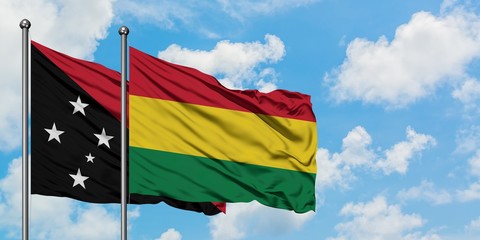 Papua New Guinea and Bolivia flag waving in the wind against white cloudy blue sky together. Diplomacy concept, international relations.