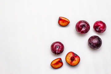 Ripe large purple plums. Fresh whole fruits, half sliced, seeds. Isolated on white background