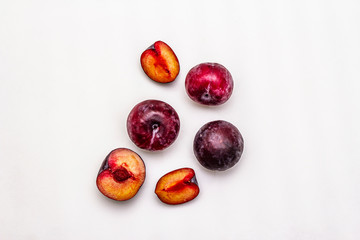 Ripe large purple plums. Fresh whole fruits, half sliced, seeds. Isolated on white background