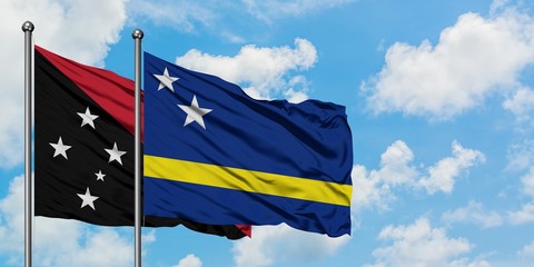 Papua New Guinea and Curacao flag waving in the wind against white cloudy blue sky together. Diplomacy concept, international relations.