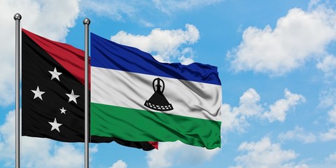 Papua New Guinea and Lesotho flag waving in the wind against white cloudy blue sky together....