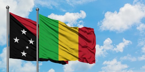 Papua New Guinea and Mali flag waving in the wind against white cloudy blue sky together. Diplomacy concept, international relations.