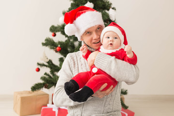 Father with his baby boy wearing Santa hats celebrating Christmas.