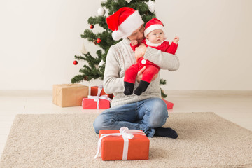 Father with his baby boy wearing Santa hats celebrating Christmas.