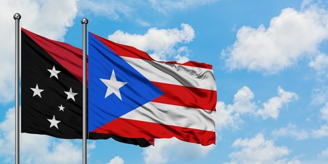 Papua New Guinea and Puerto Rico flag waving in the wind against white cloudy blue sky together. Diplomacy concept, international relations.