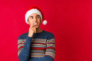 Young man on christmas day showing a copy space on a palm and holding another hand on waist.