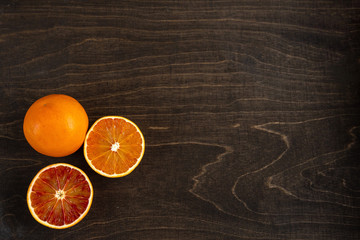 A closeup photo of vibrant organic blood oranges on a dark background with copy space.