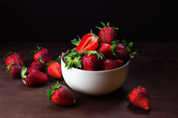 Fresh strawberries in ceramic bowl on dark wooden background. Selective focus. - Image