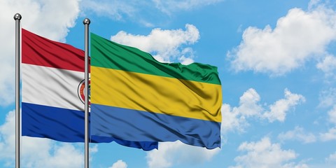 Paraguay and Gabon flag waving in the wind against white cloudy blue sky together. Diplomacy concept, international relations.