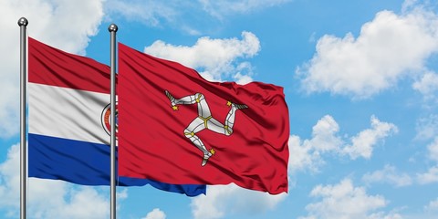 Paraguay and Isle Of Man flag waving in the wind against white cloudy blue sky together. Diplomacy concept, international relations.